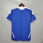 Camiseta de fútbol retro azul con detalles blancos, vista trasera en percha