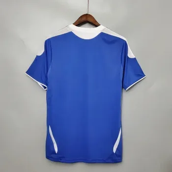 Camiseta de fútbol retro azul con detalles blancos, vista trasera en percha