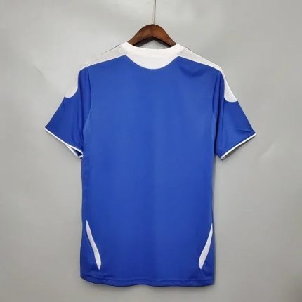 Camiseta de fútbol retro azul con detalles blancos, vista trasera en percha