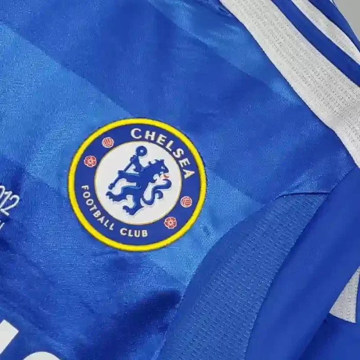 Camiseta retro azul de fútbol con escudo del Chelsea FC bordado y detalles blancos.