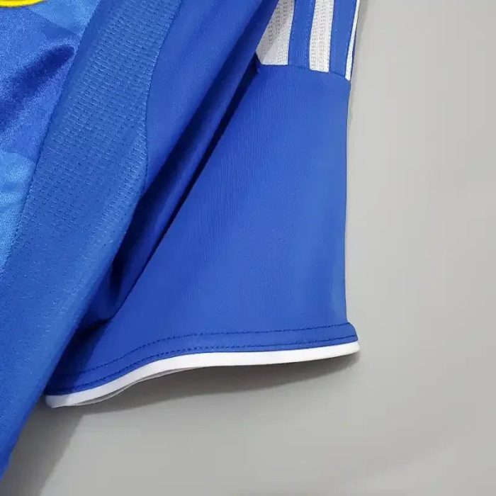 Detalle de manga de camiseta de fútbol retro azul con ribete blanco y franjas blancas