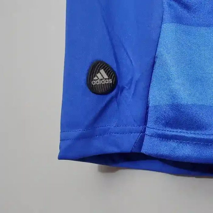 Detalle de manga de camiseta azul retro de fútbol con logo de Adidas