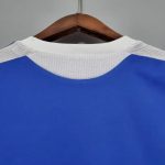 Detalle de la parte trasera de una camiseta de fútbol retro azul con cuello blanco.